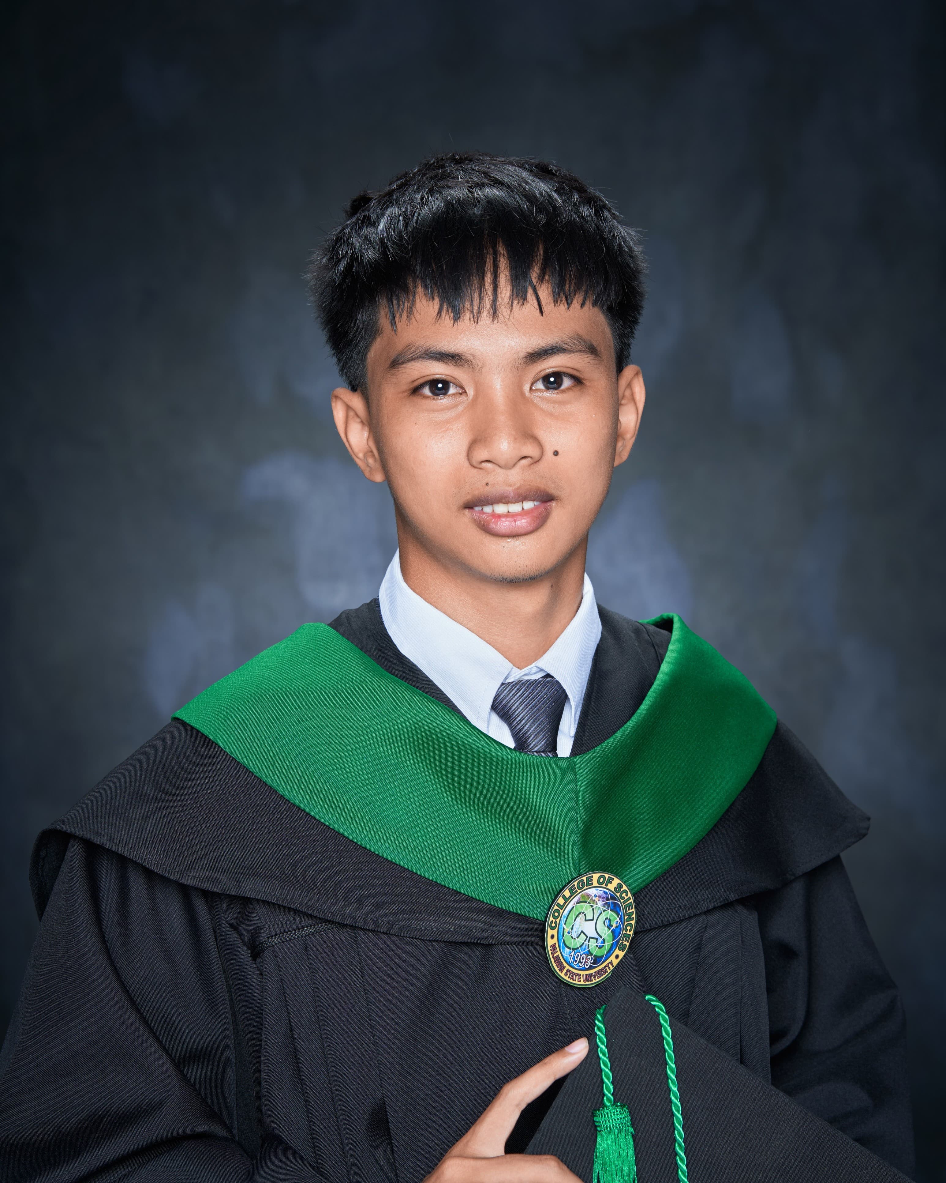 Elsid Rick Panolino in a graduation toga with a green hood and College of Sciences medal, Palawan State University